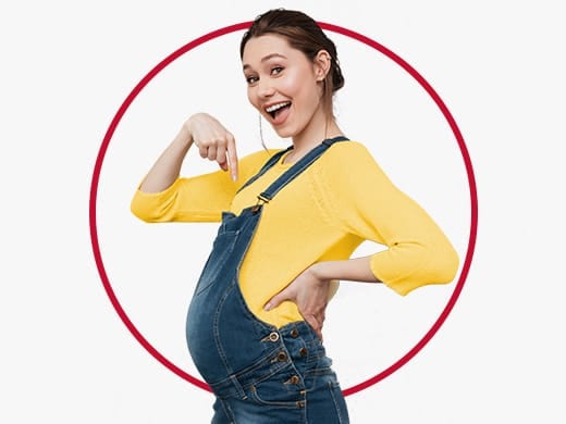 Mulher jovem feliz vestindo um vestido de avental amarelo e apontando para a barriga