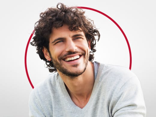 Homem jovem sorridente de moletom cinza, feliz após o tratamento de candidíase Canesten