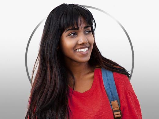 Mulher jovem sorridente de cabelos escuros, vestindo uma camiseta vermelha, feliz após o tratamento para cistite com Gino-Canesten